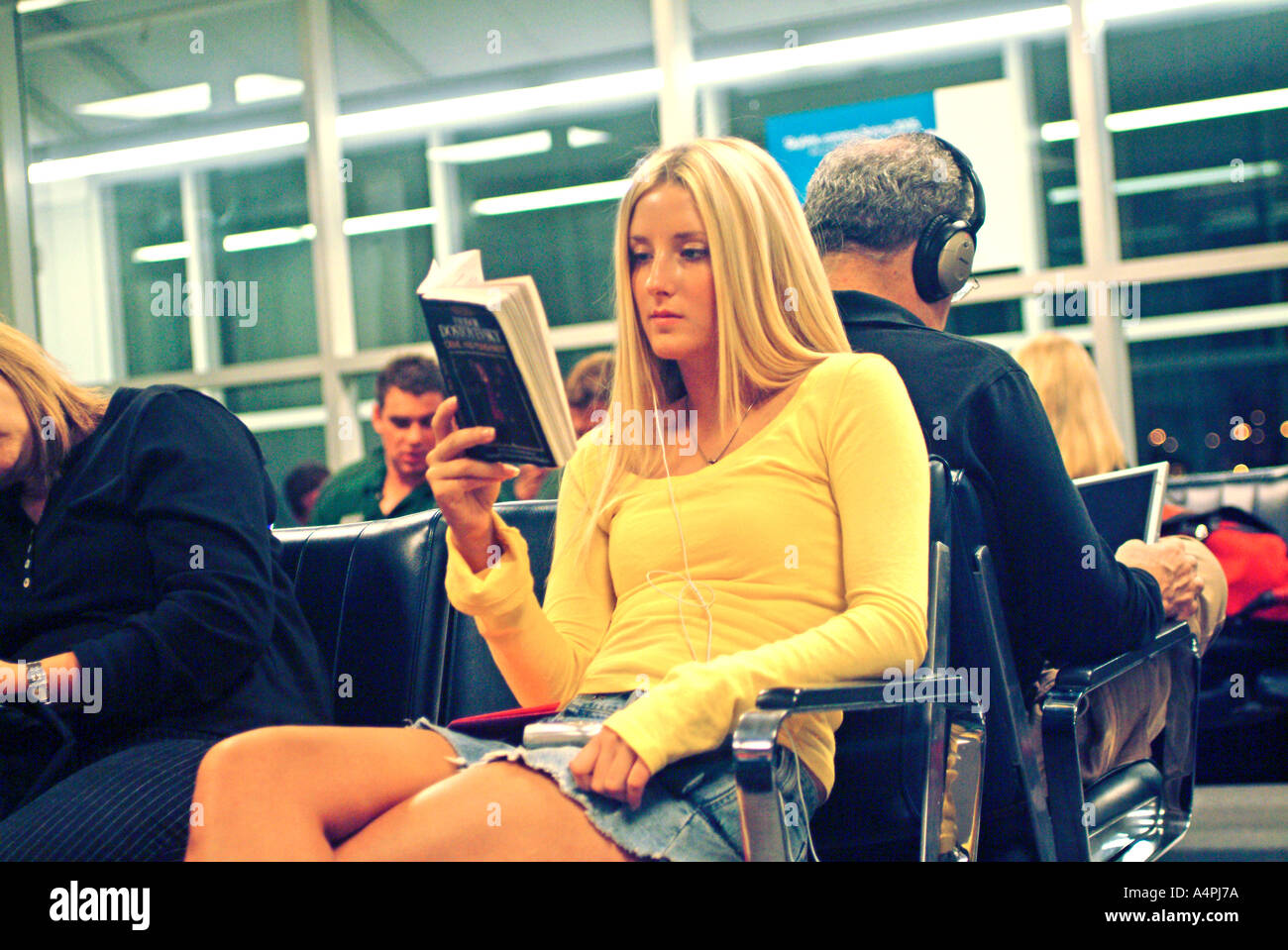 young woman sitting in airport terminal reading a book Stock Photo - Alamy