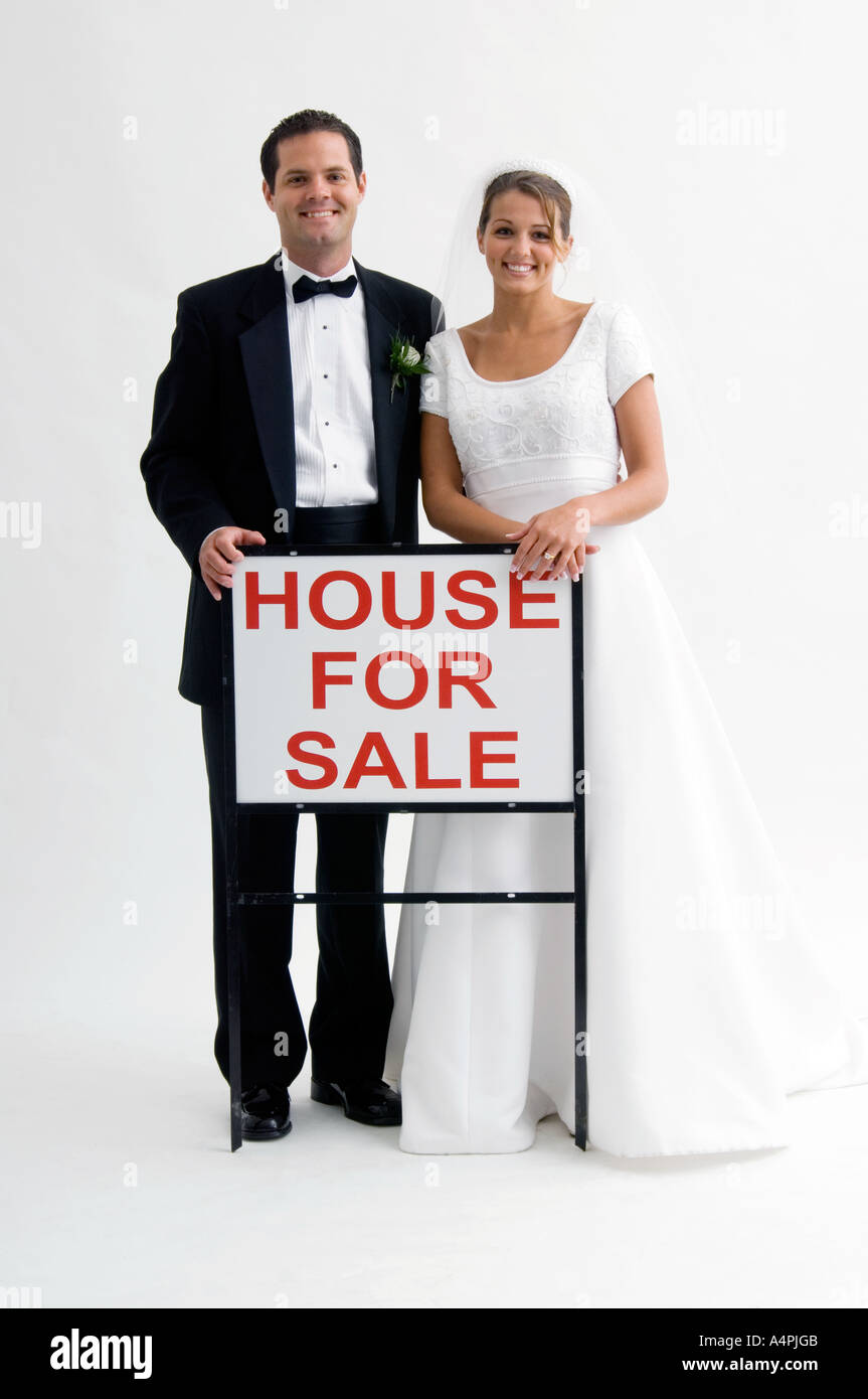 Bride and groom holding house for sale sign Stock Photo - Alamy