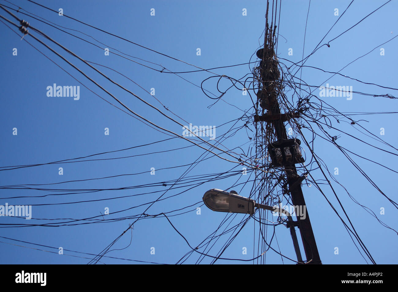 Stealing electricity ; Power theft ; Electricity pole ; Electric pole ; street light pole ; pole complicated wiring ; India ; Indian ; Asia ; Asian Stock Photo