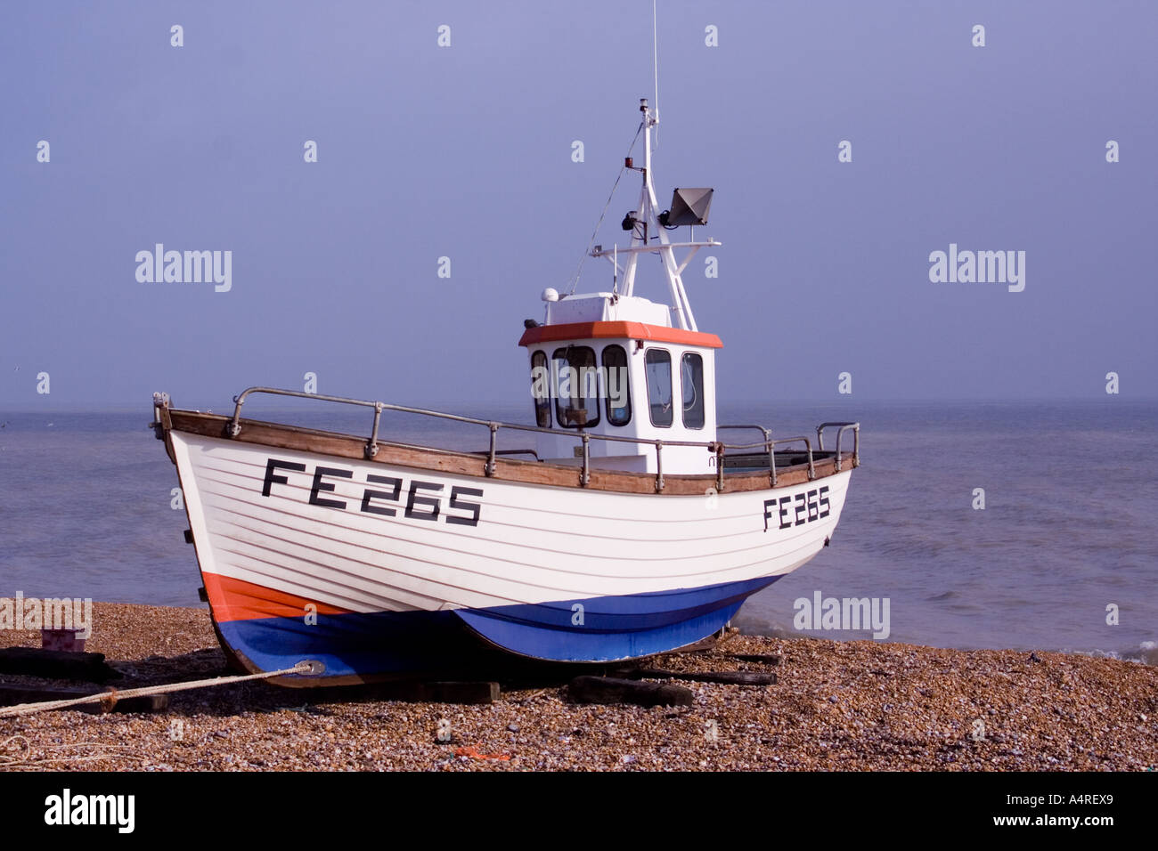 Small red, white and blue fishing boat on the beach at Dungeness in