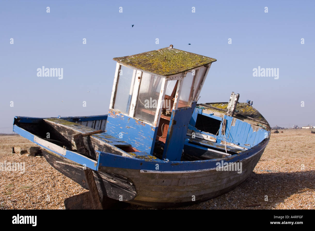 Rear view of abandoned fishing boat decaying on the shingle beach at ...