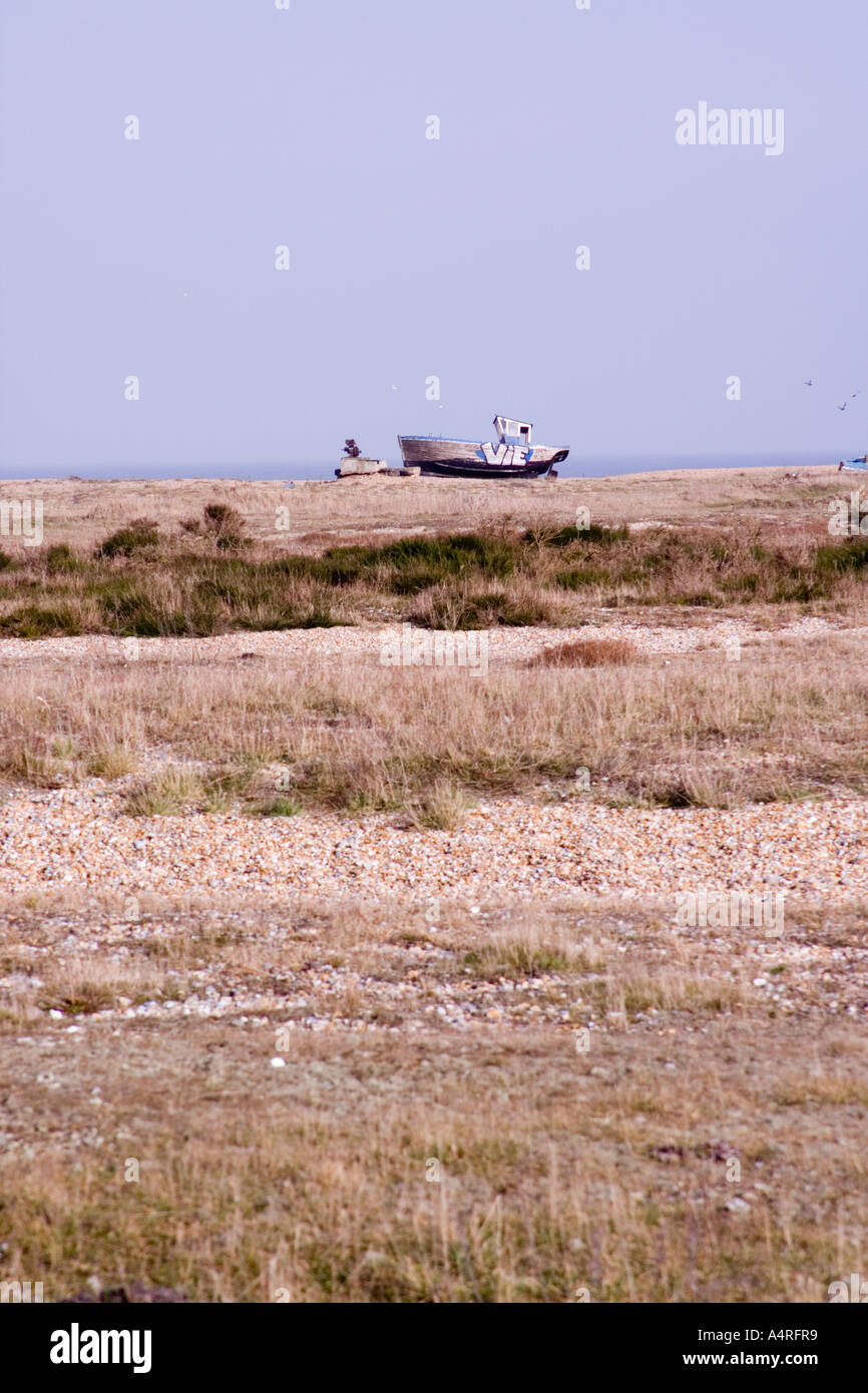 Abandoned fishing boat in the distance on the shingle beach at ...