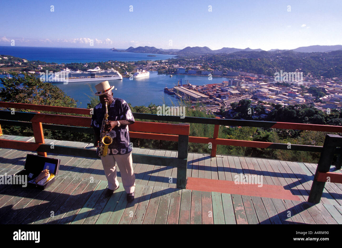A man playing a saxophone at Morne Fortune with a view over Castries St Lucia Stock Photo