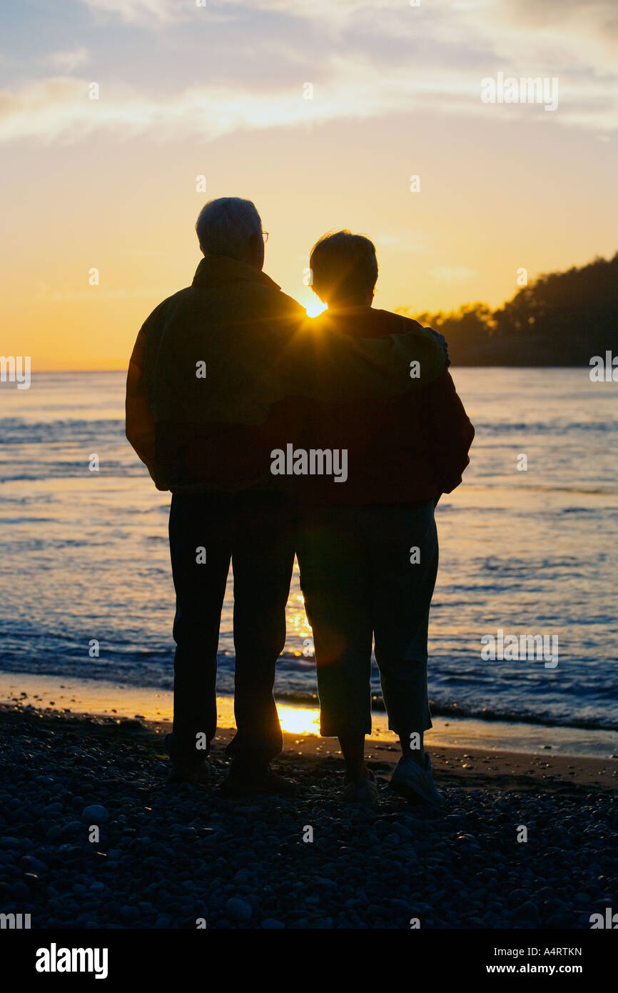 Silhouette of couple watching sunset on beach Stock Photo - Alamy