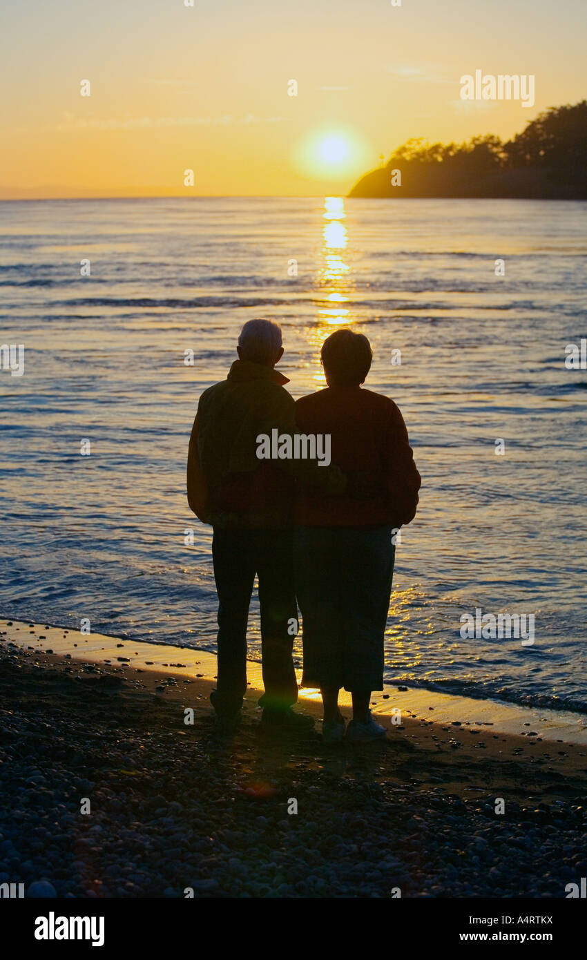 Silhouette of couple watching sunset on beach Stock Photo - Alamy