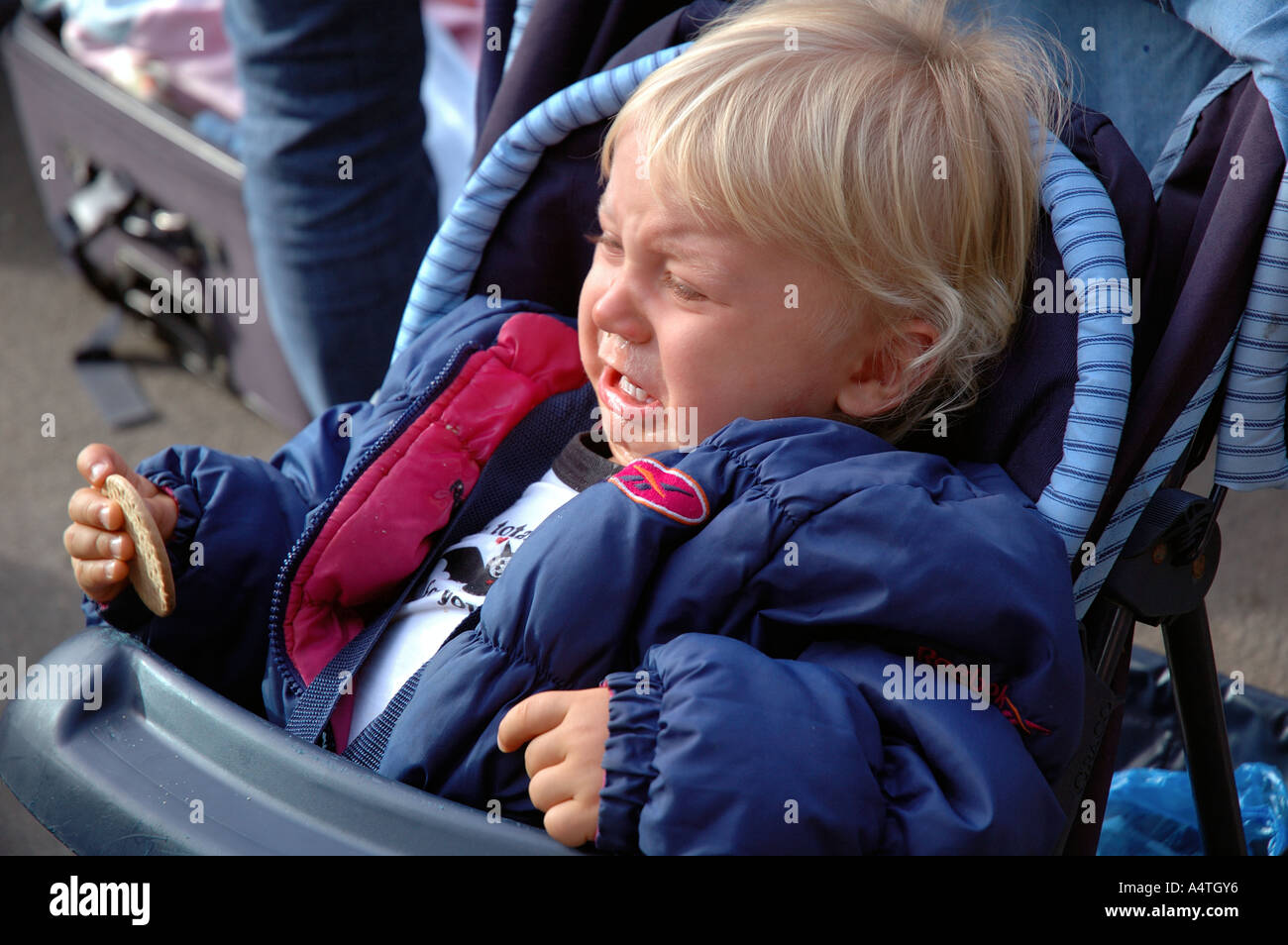 Child in tears in a pushchair. Stock Photo