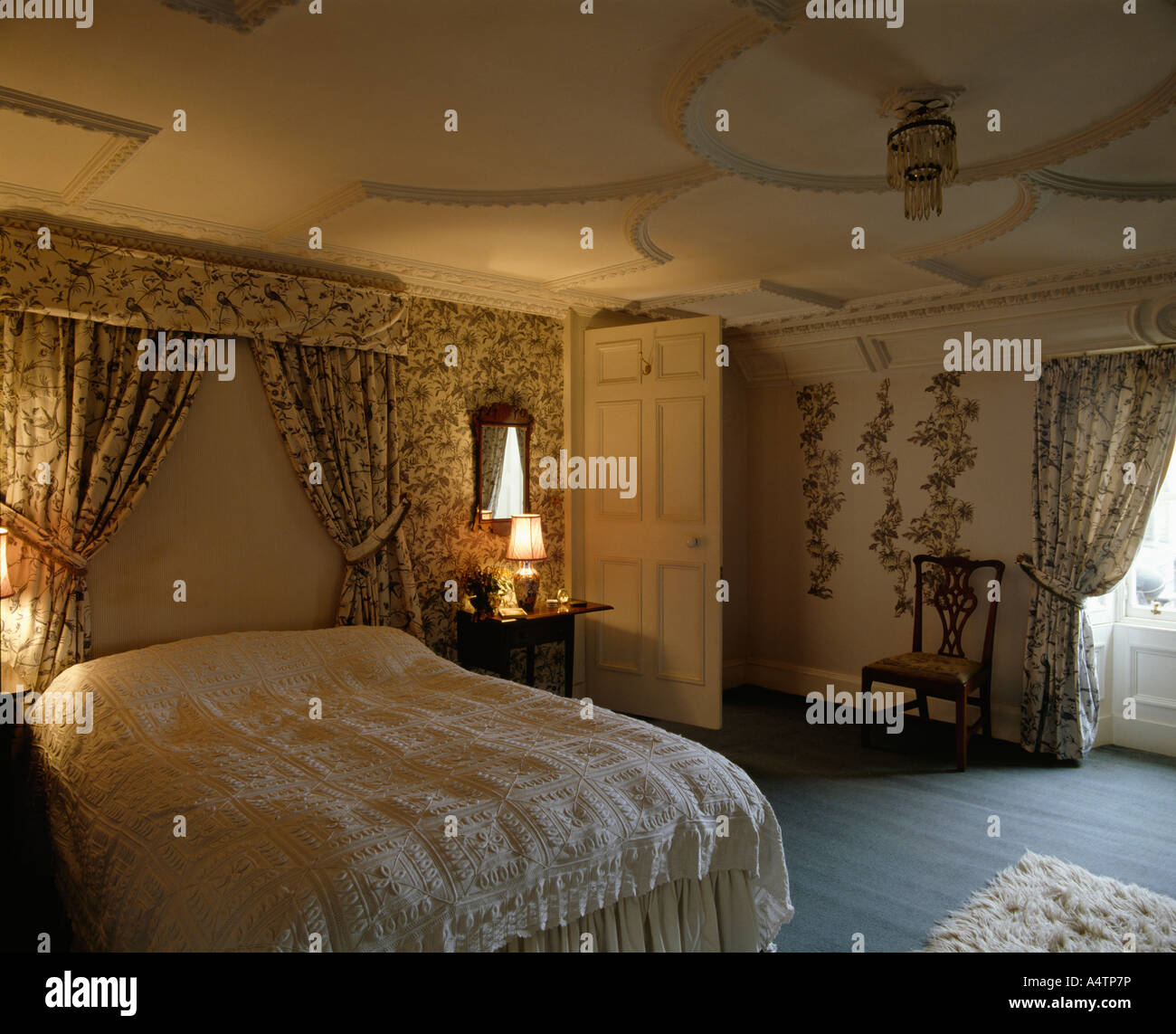 Bed With Drapes And Floral Linen In Country Bedroom With Ornate