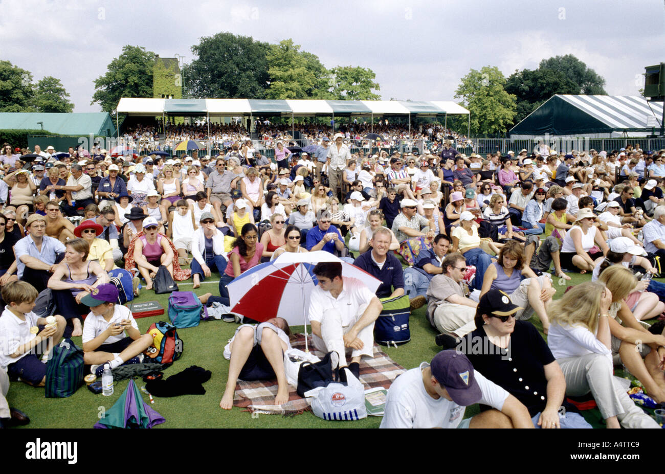 Crowds sitting on outside courts watching a screen at All England Tennis Club Wimbledon London Stock Photo
