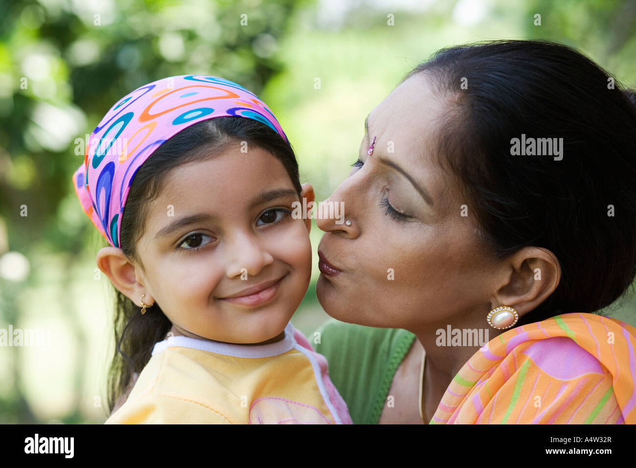 Woman kissing her granddaughter on the cheek outdoors Stock Photo