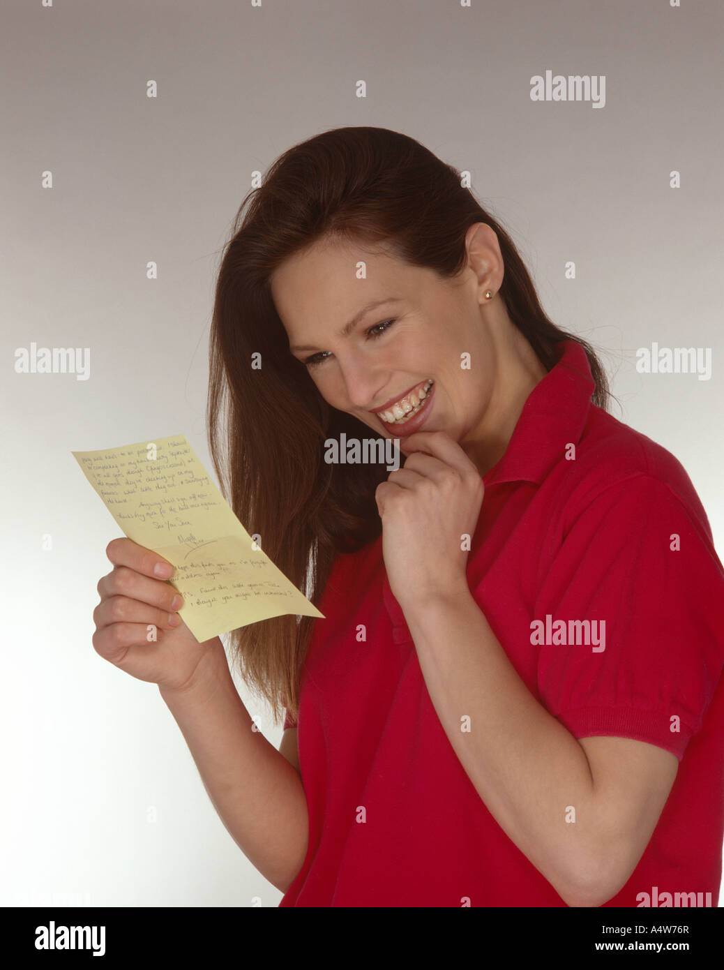 GIRL IN RED TOP READING LETTER Stock Photo