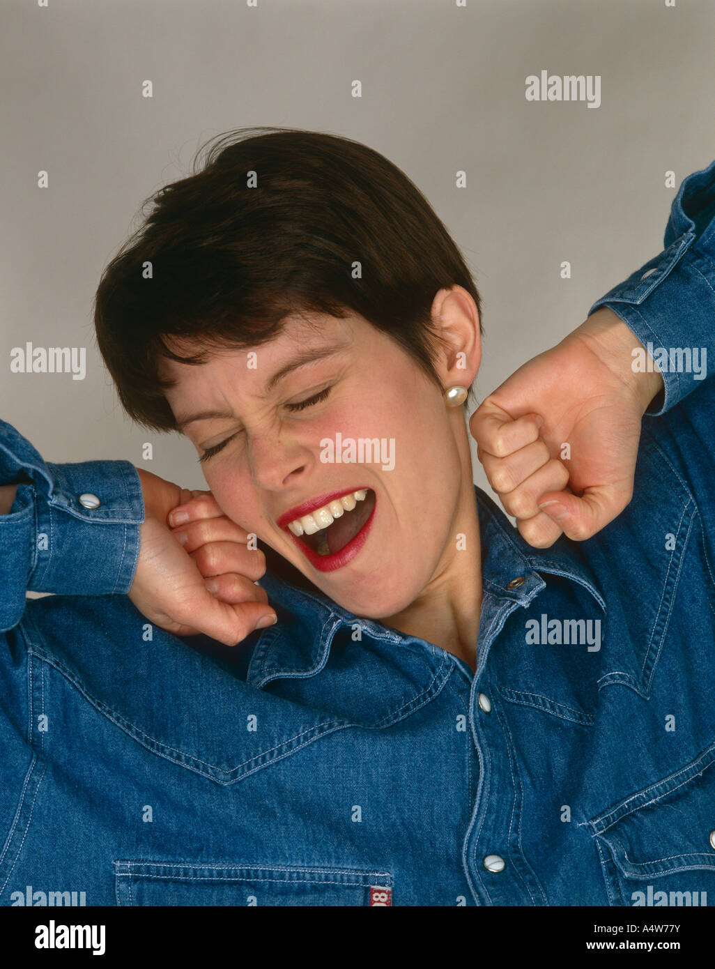 A GIRL IN BLUE SHIRT STRETCHING AND YAWNING Stock Photo