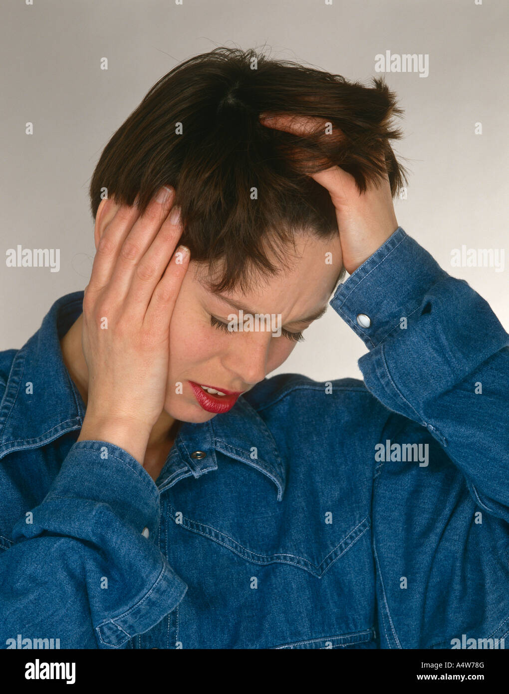 GIRL IN BLUE SHIRT HOLDING HEAD AS IF WITH HEADACHE Stock Photo
