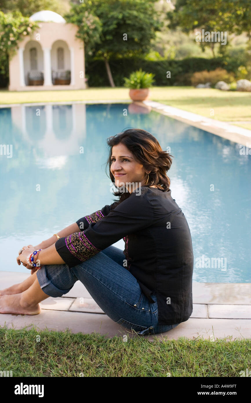 Woman sitting at the edge of swimming pool Stock Photo - Alamy