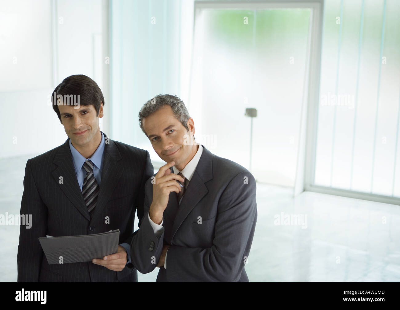 Two businessmen standing side by side, one holding file Stock Photo