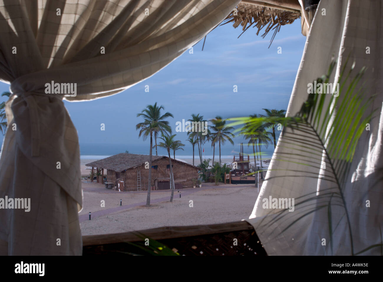 View on ocean sunrise through bungalow open curtains window Stock Photo