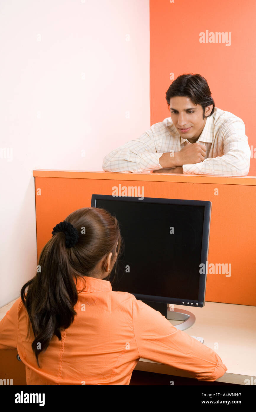 Businessman talking to female coworker over cubicle wall Stock Photo