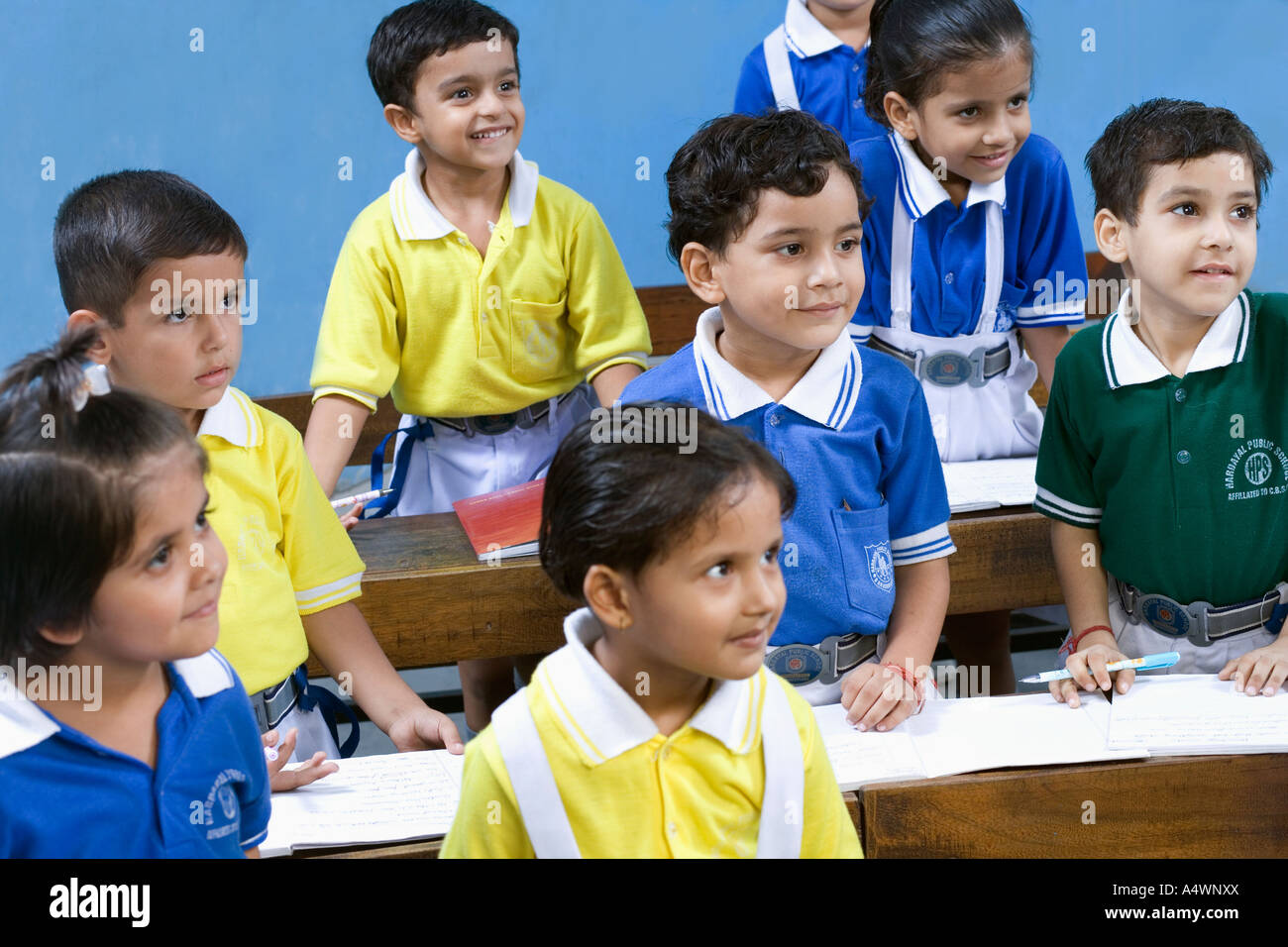 Children standing at desks in classroom Stock Photo