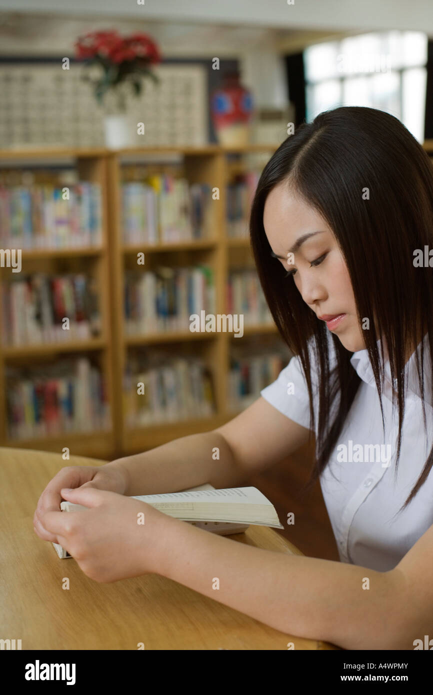 Female student reading at a table stock photo alamy