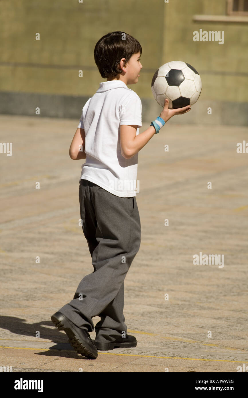 Young student carrying soccer ball in courtyard Stock Photo