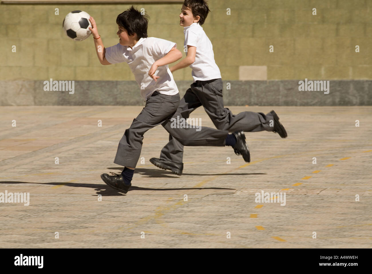 Young students playing basketball with a soccer ball in courtyard Stock Photo