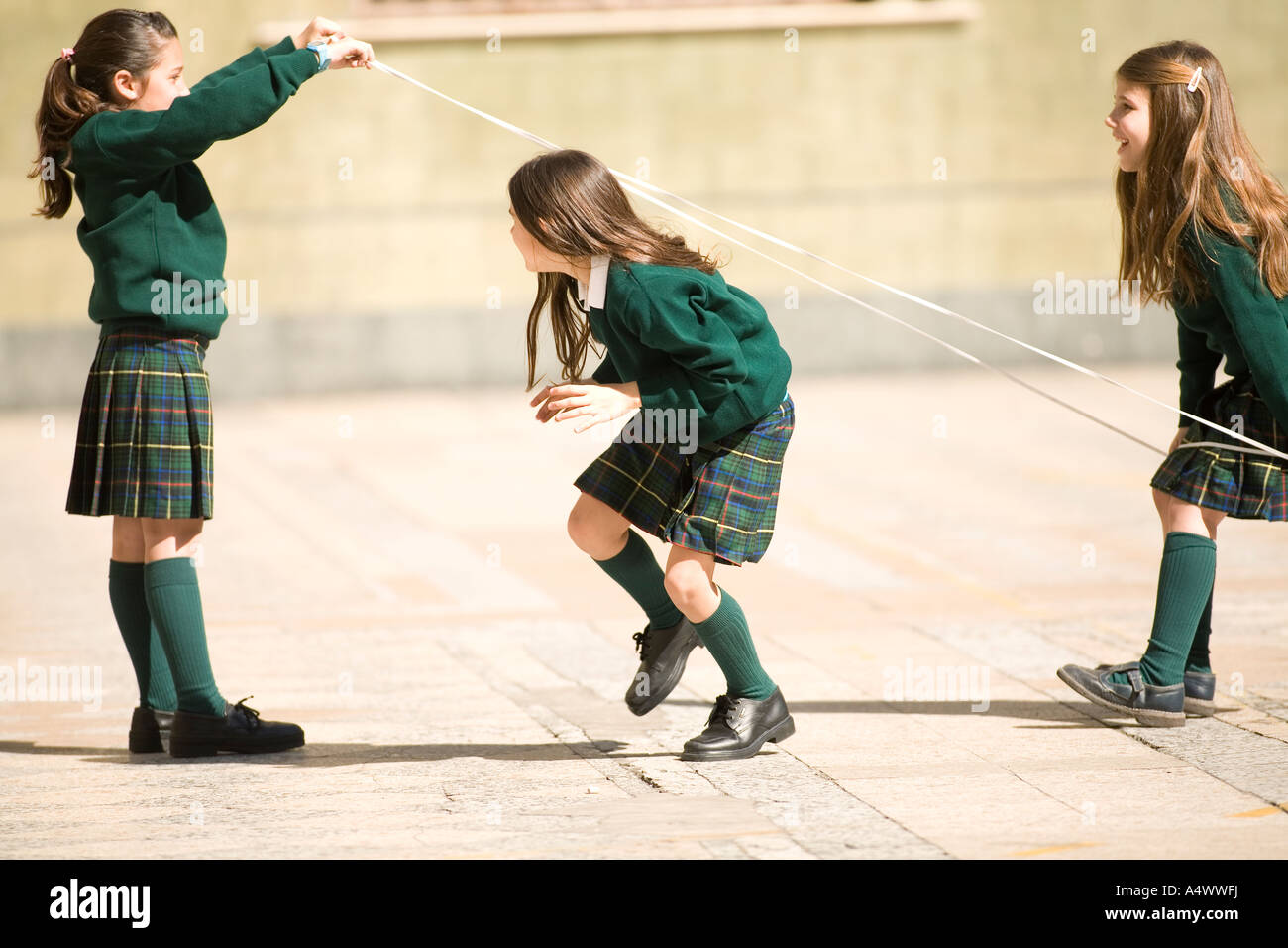 Young students playing with rope in courtyard Stock Photo - Alamy