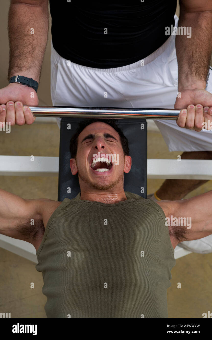 Personal trainer helping man bench press Stock Photo - Alamy
