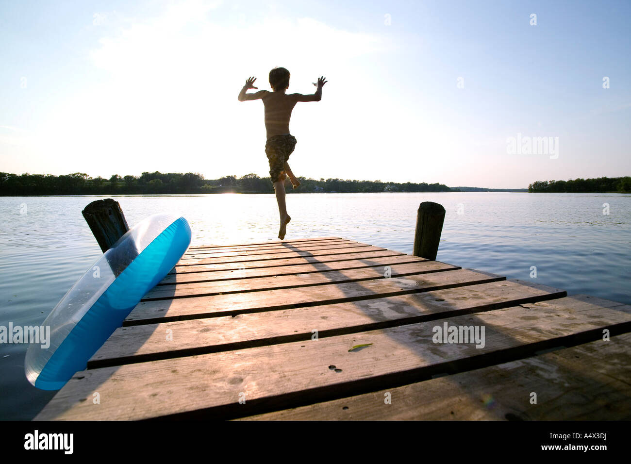 Kid jumping off a dock into a Lake Stock Photo Alamy