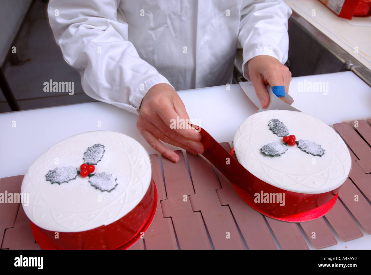 PRODUCTION LINE WORKERS ADDING THE FINISHING RIBBON TO CHRISTMAS CAKES DESTINED FOR UK SUPERMARKETS Stock Photo