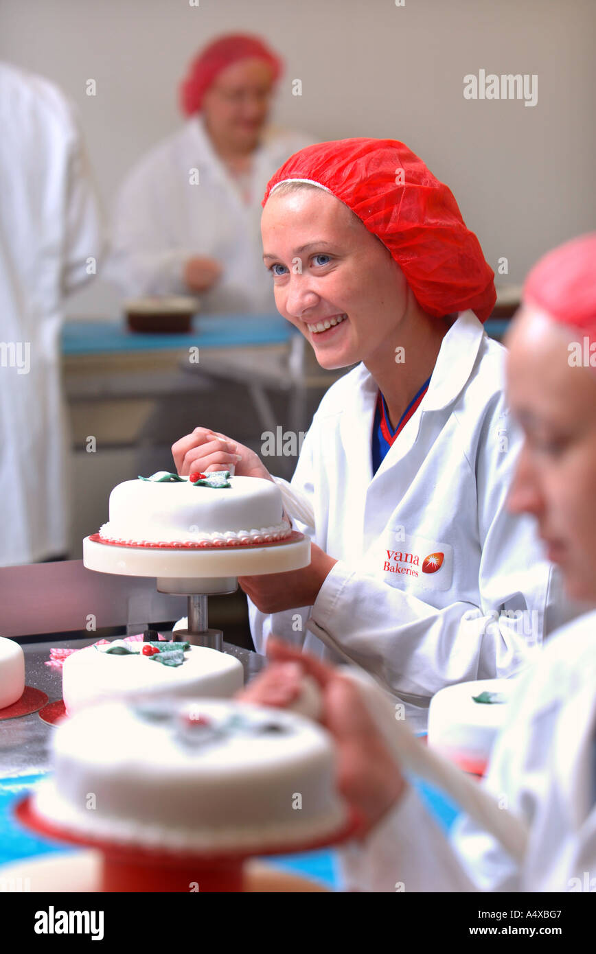 PRODUCTION LINE WORKERS ADDING THE FINISHING TOUCHES TO CHRISTMAS CAKES DESTINED FOR UK SUPERMARKETS Stock Photo