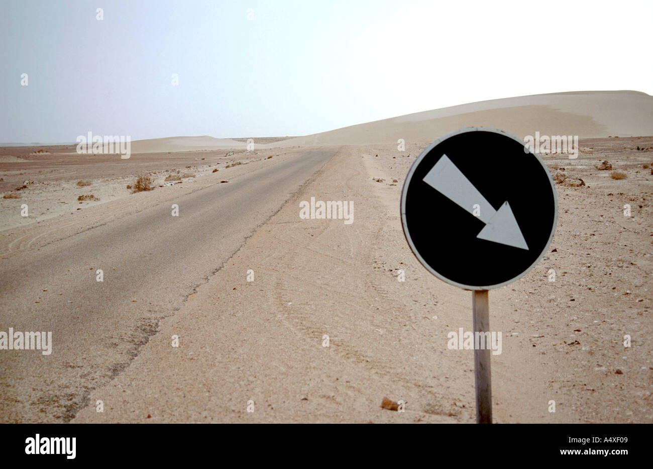 A sand dune that has covered the road in Morocco, necessitating a permanent detour. Stock Photo