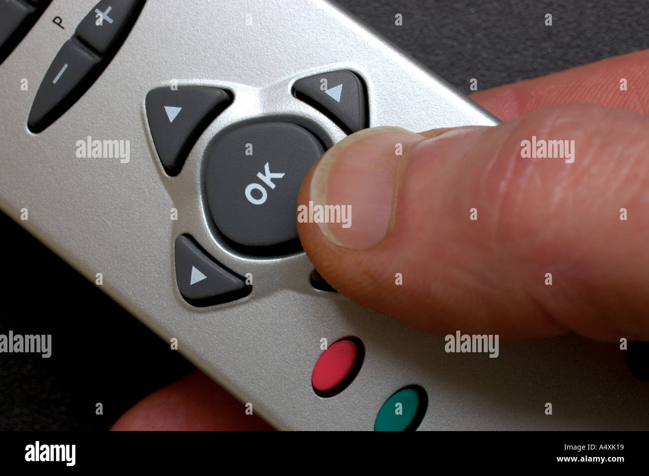 Hand holding remote control thumb pressing ok button Stock Photo