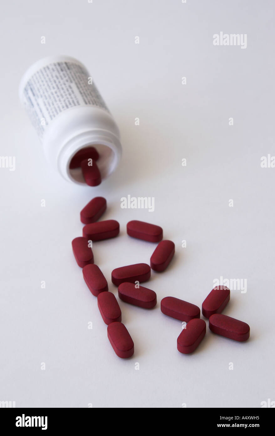 Drugs spilled out of a pill bottle forming a prescription sign, writing on the bottle unreadable Stock Photo