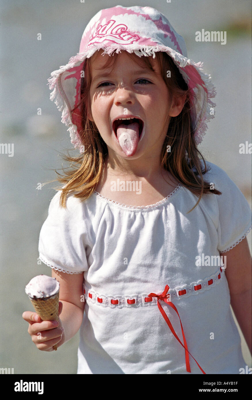 A young girl shows her tongue whilst eating an icecream Stock Photo Alamy
