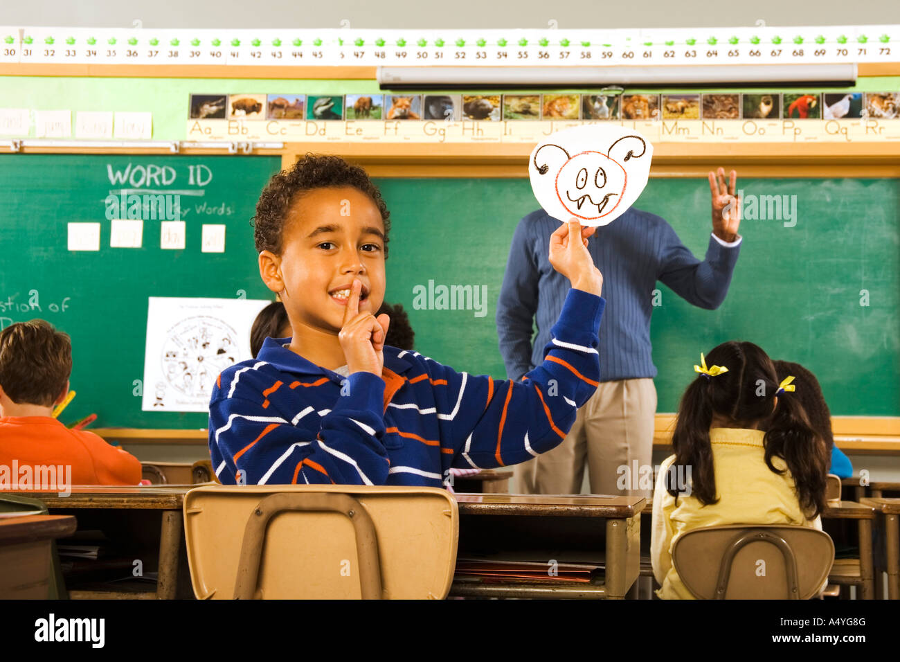 Boy holding drawing over teacher’s face Stock Photo