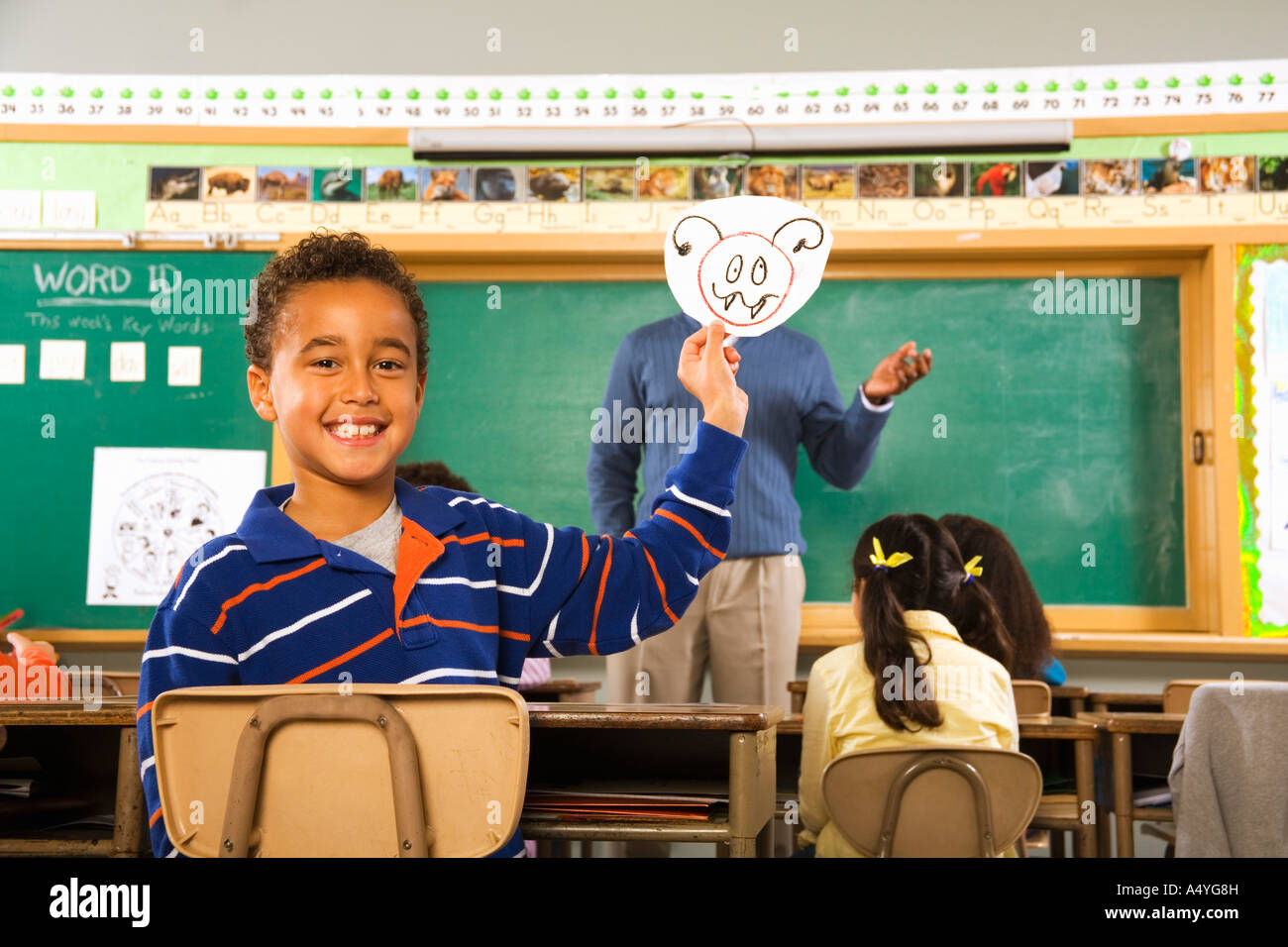 Boy holding drawing over teacher’s face Stock Photo