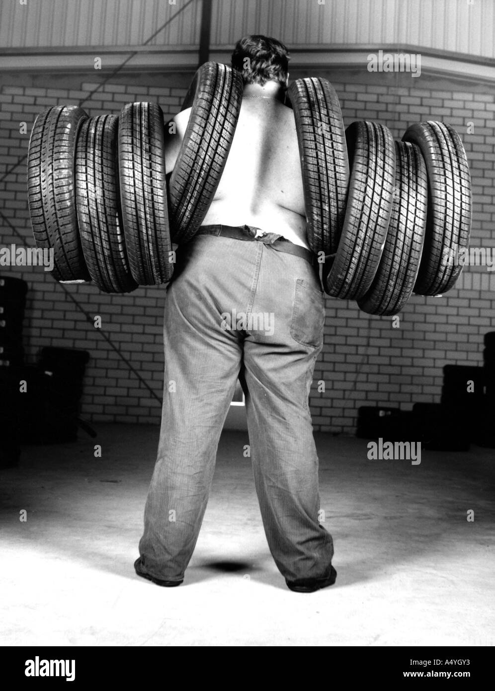 Man carrying 8 tyres Stock Photo
