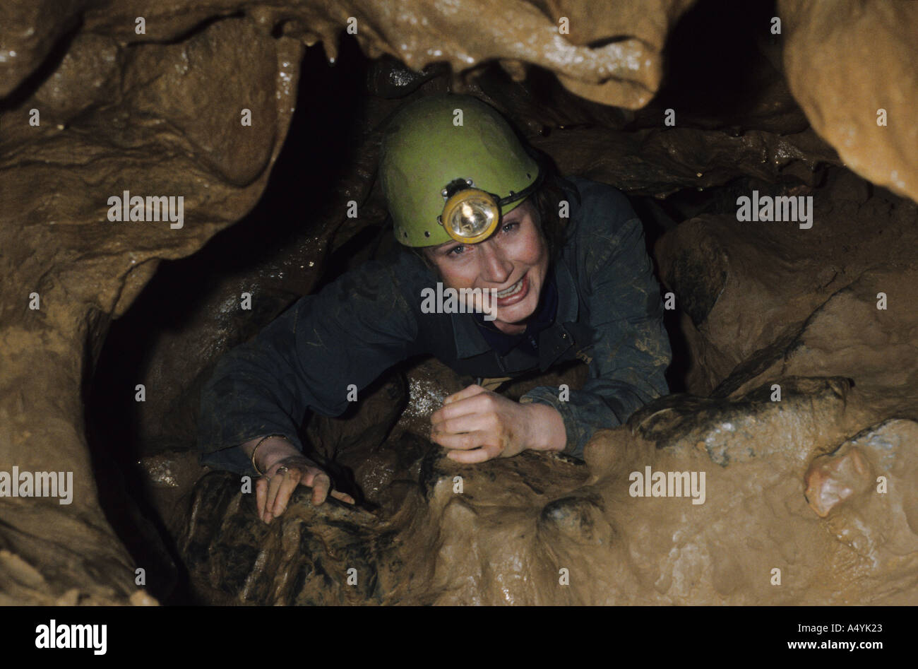 A young woman negotiates the April Fool's Squeeze in Cheddar Caves, Somerset, UK Stock Photo
