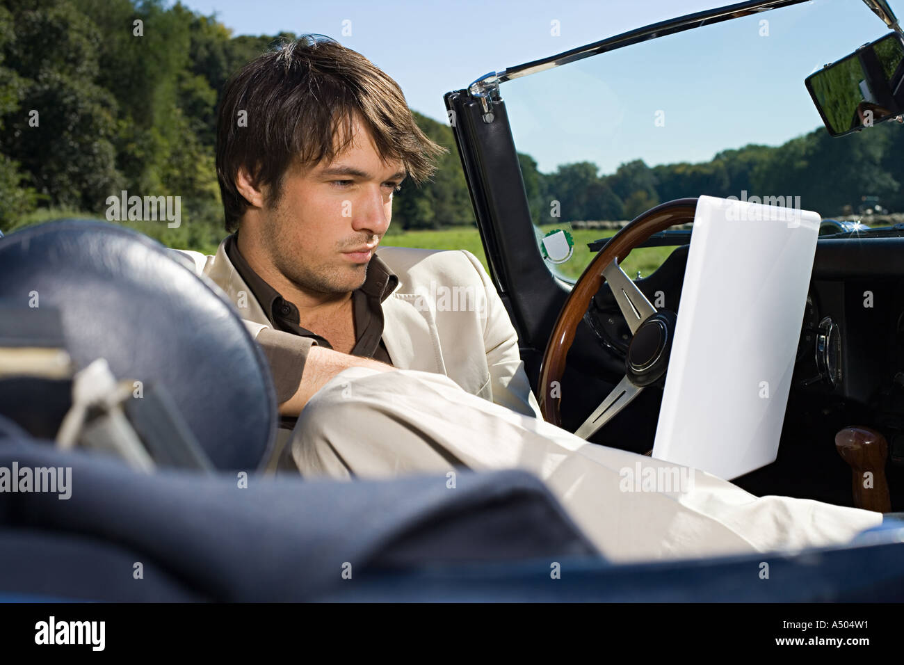Man in convertible using laptop Stock Photo