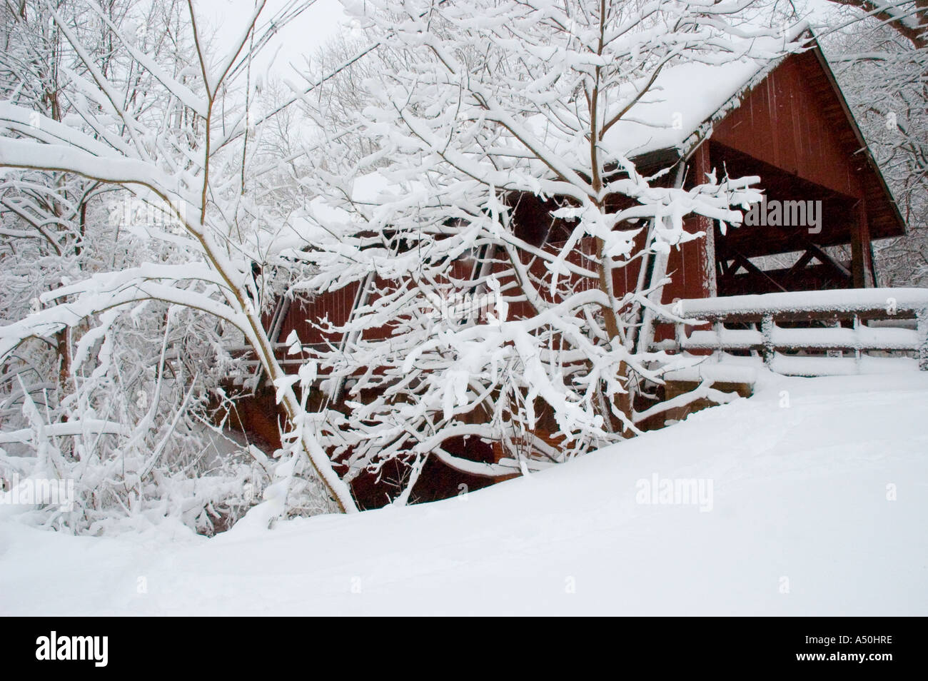 A winter snowstorm dumps several inches / nearly a foot of snow on a red covered bridge in New Jersey United States Stock Photo
