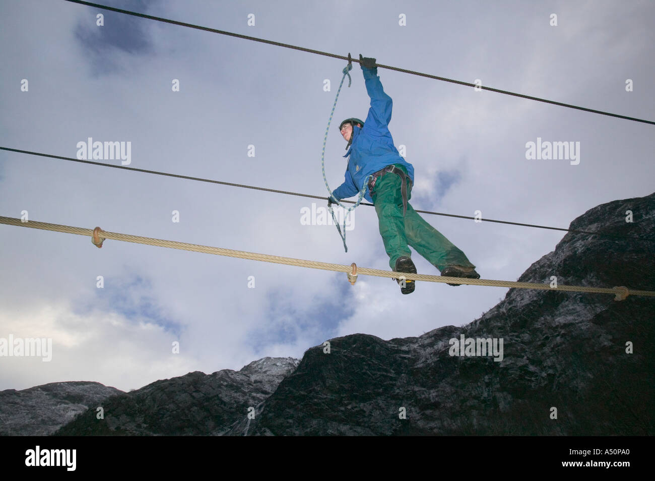 a climber crosses the steel rope bridge across the river Nevis at