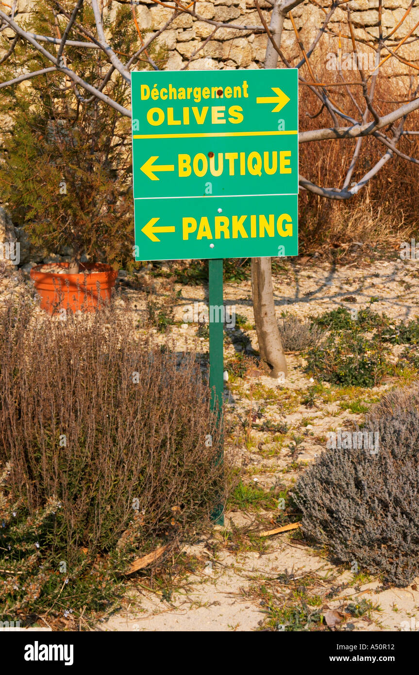 Signs showing the shop, olive delivery, parking with shrubs, rosemary