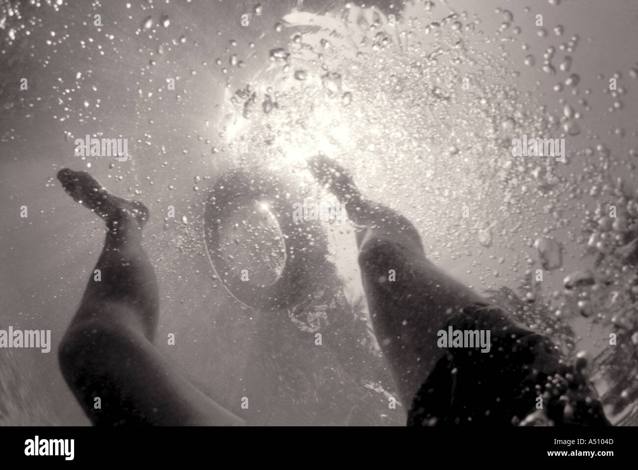 Upward view from underwater of swimmers legs and life saving ring floating on the surface Stock Photo