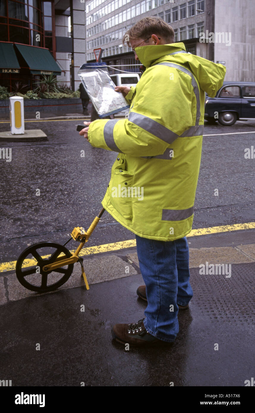 London street scene surveyor man working with measuring wheel tool on