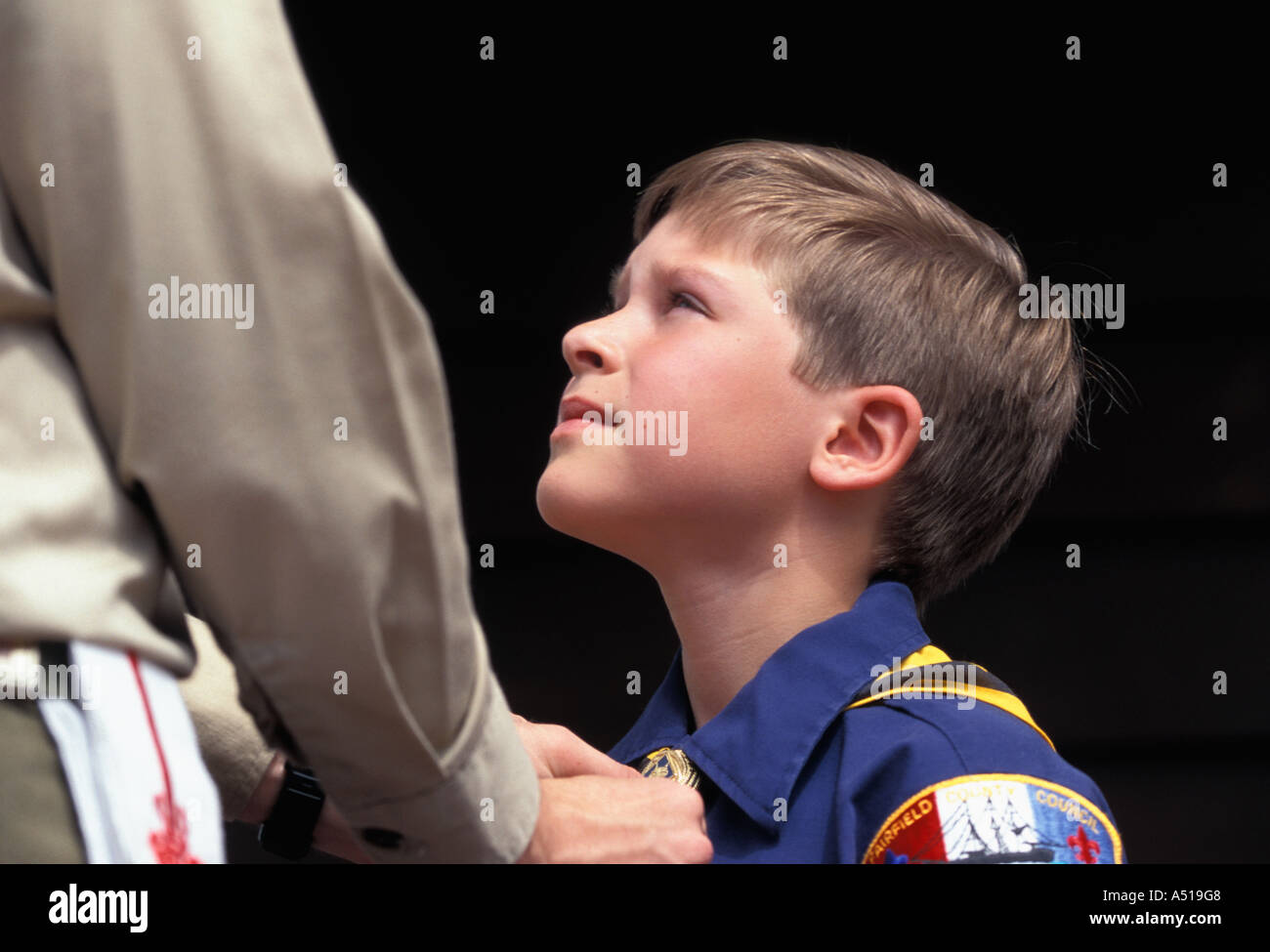 Boy Scout straightening neckerchief of Cub Scout User needs to obtain