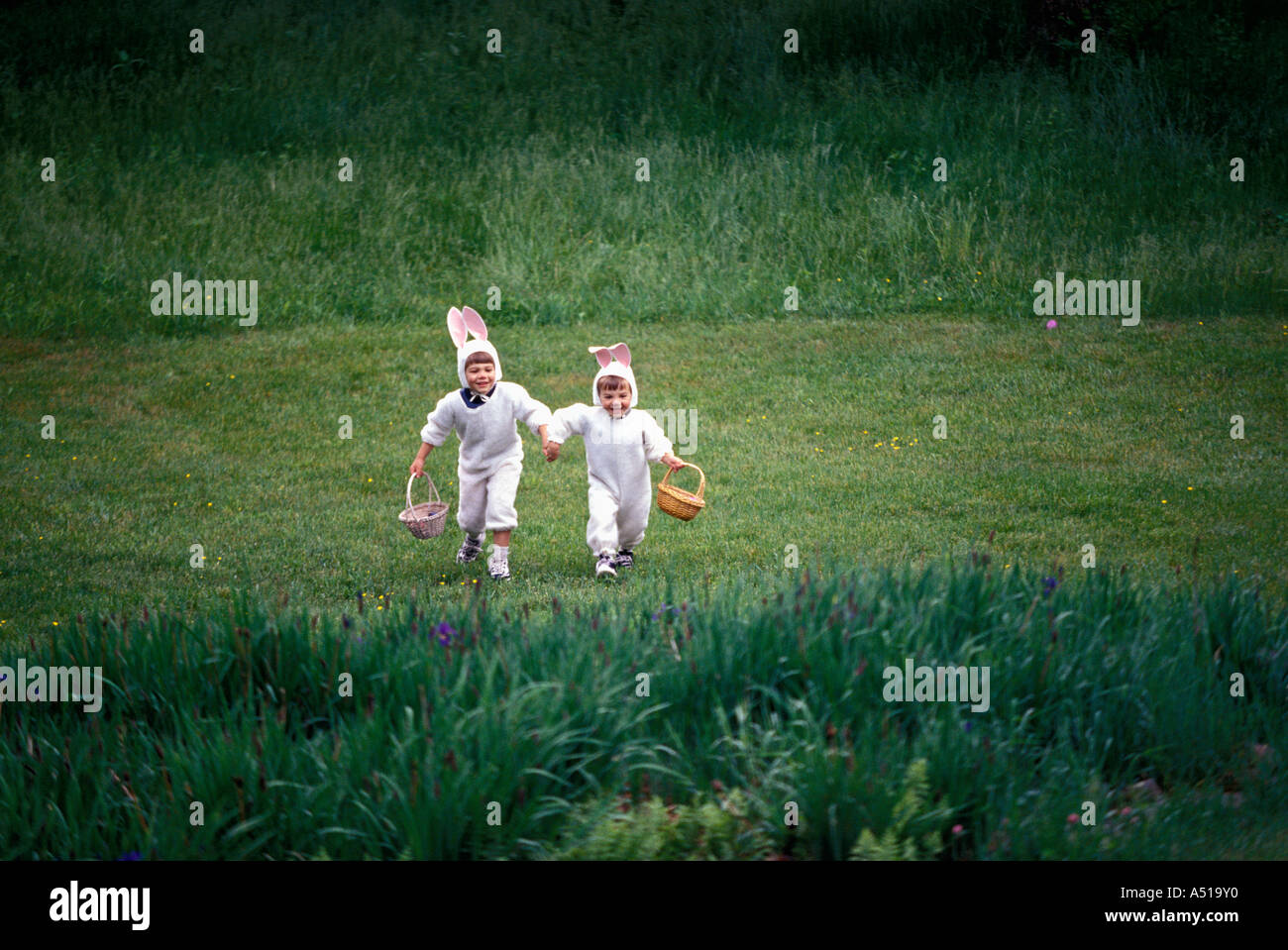 Two brothers in bunny costumes searching for Easter eggs Stock Photo