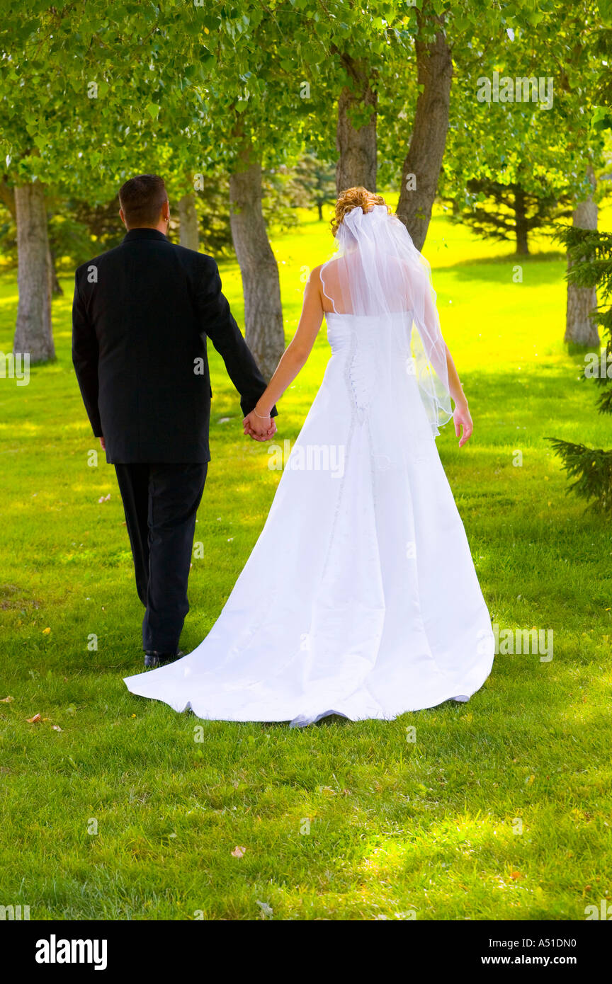 Bride and groom walking hand in hand Stock Photo - Alamy