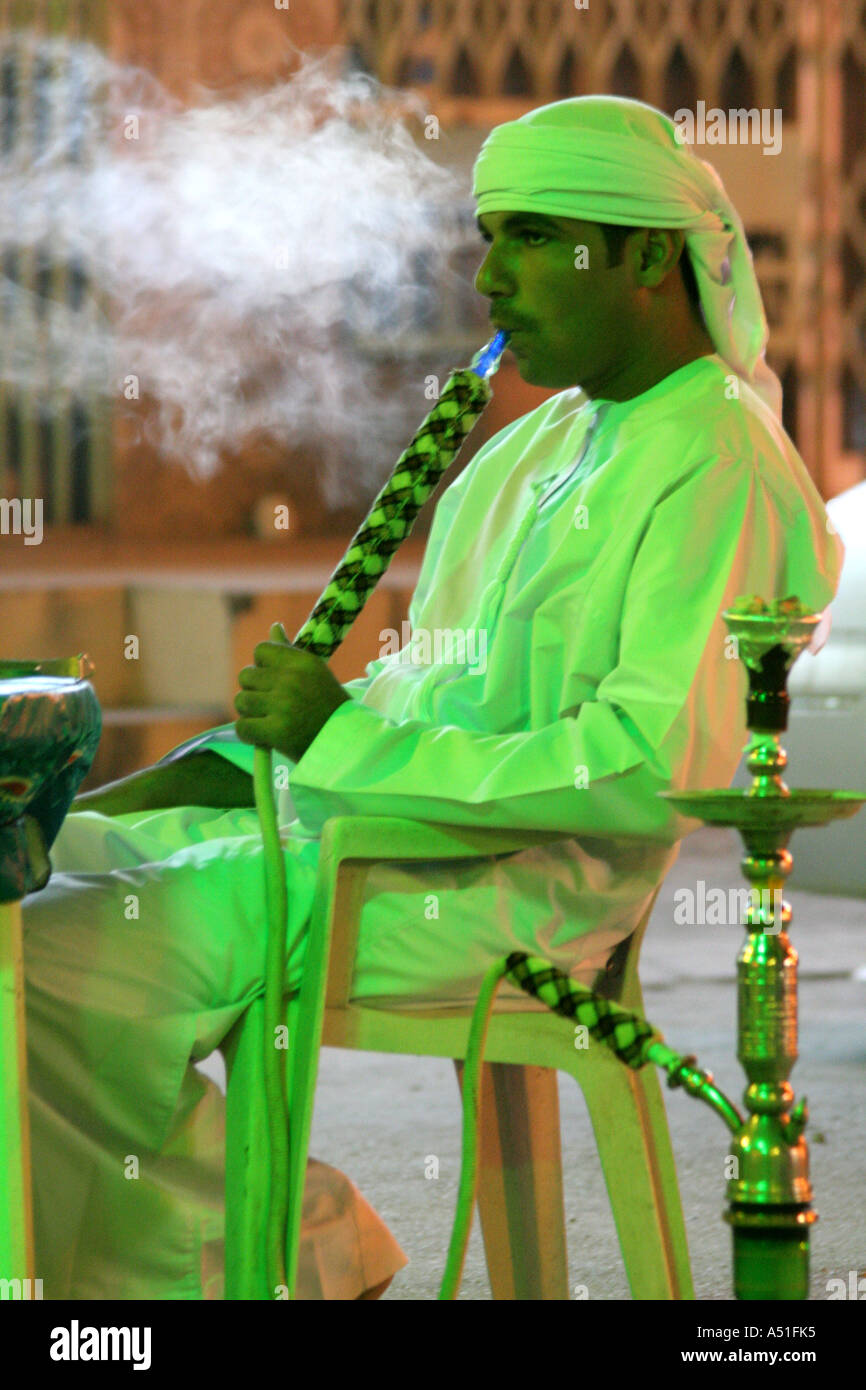 Arab man puffing on a sheesha at an outdoor resaurant in Salalah, Oman Stock Photo