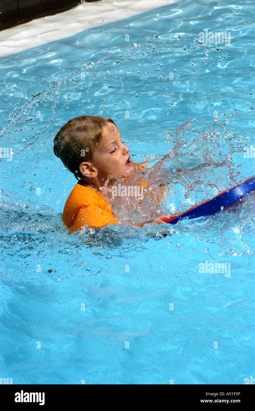 Boy playing swimming pool with boogie board young family summer vacations Stock Photo