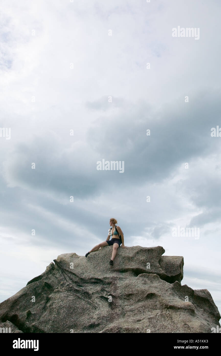Woman sitting atop granite rock Stock Photo