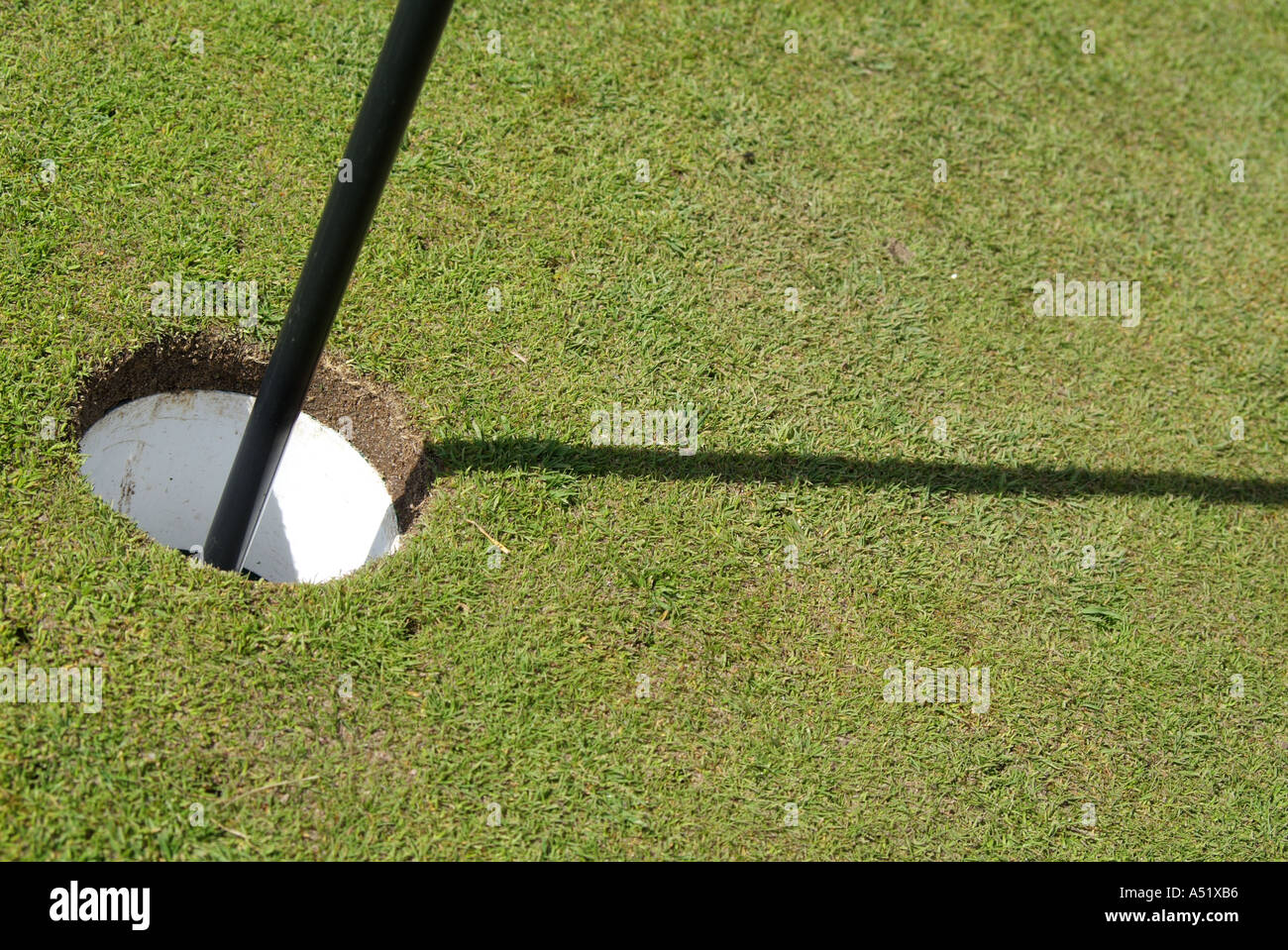 Golf putt and shadow of a golf tee and flag on the green grass. England Stock Photo